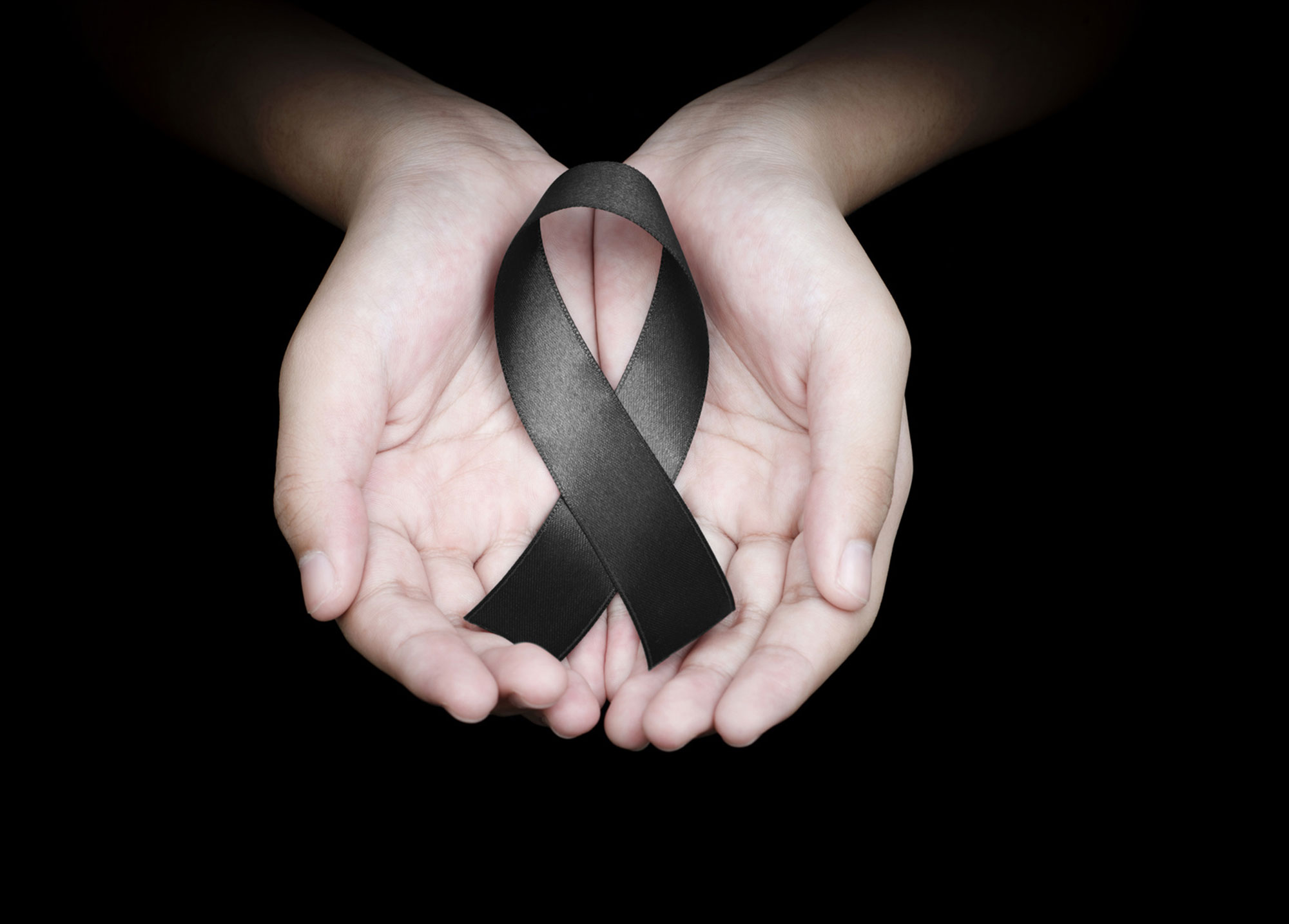 Quelle: #160526015 Hand holding black ribbon on black background mourning awareness sign © Love the wind | fotolia.com